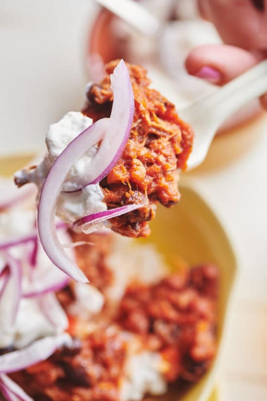 Fork with a scoop of Barbacoa Beef Chili, sour cream, and red onions.