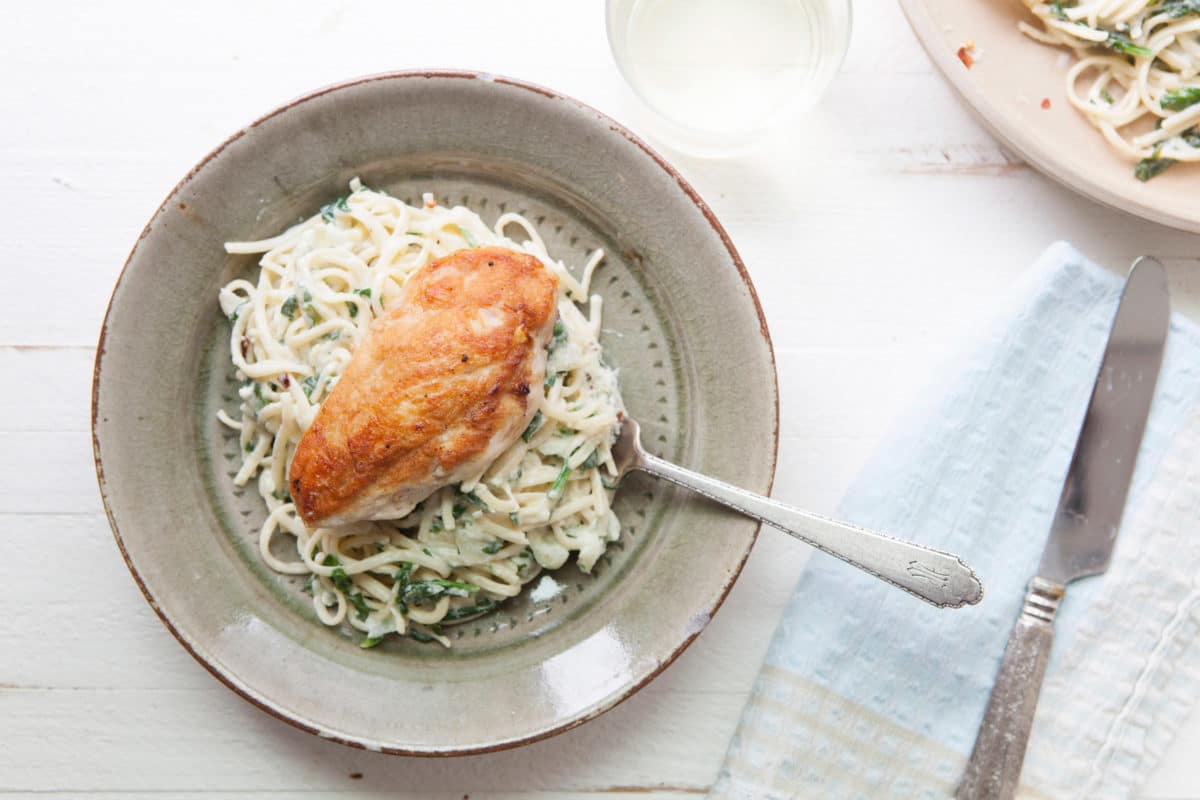 Chicken on a bed of Creamy Goat Cheese and Spinach Linguine.