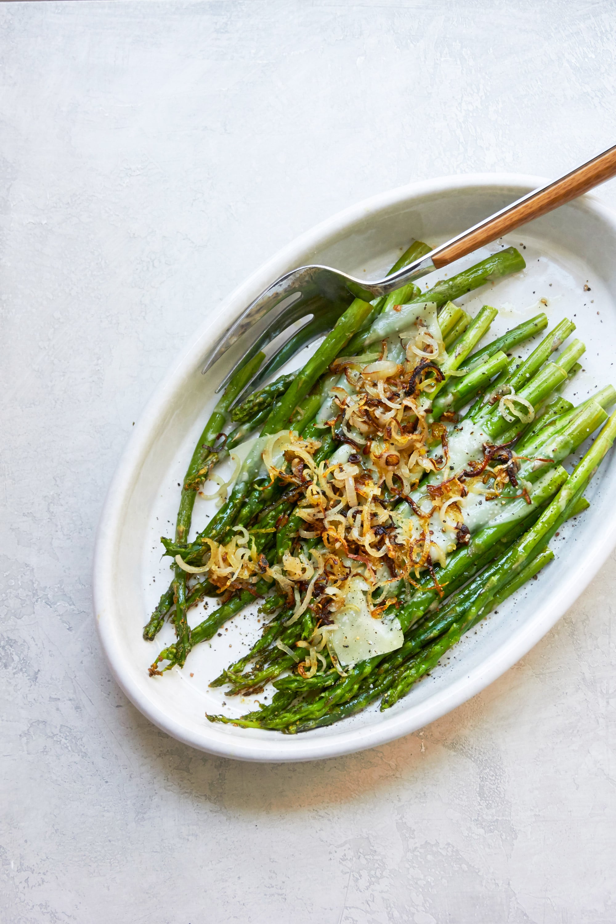 Fork on a dish of Roasted Asparagus with Shallots and Parmesan.