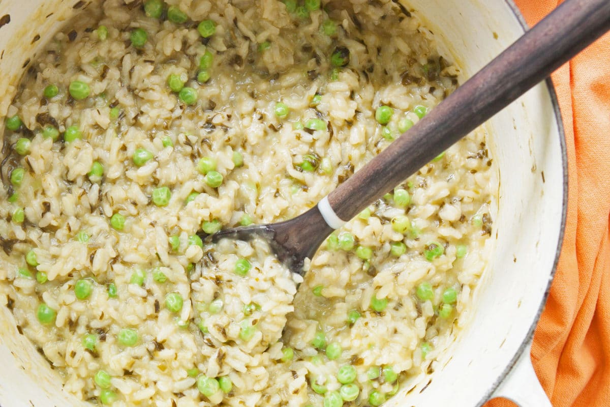 Spring Ramp and Pea Risotto in white pot with spoon.