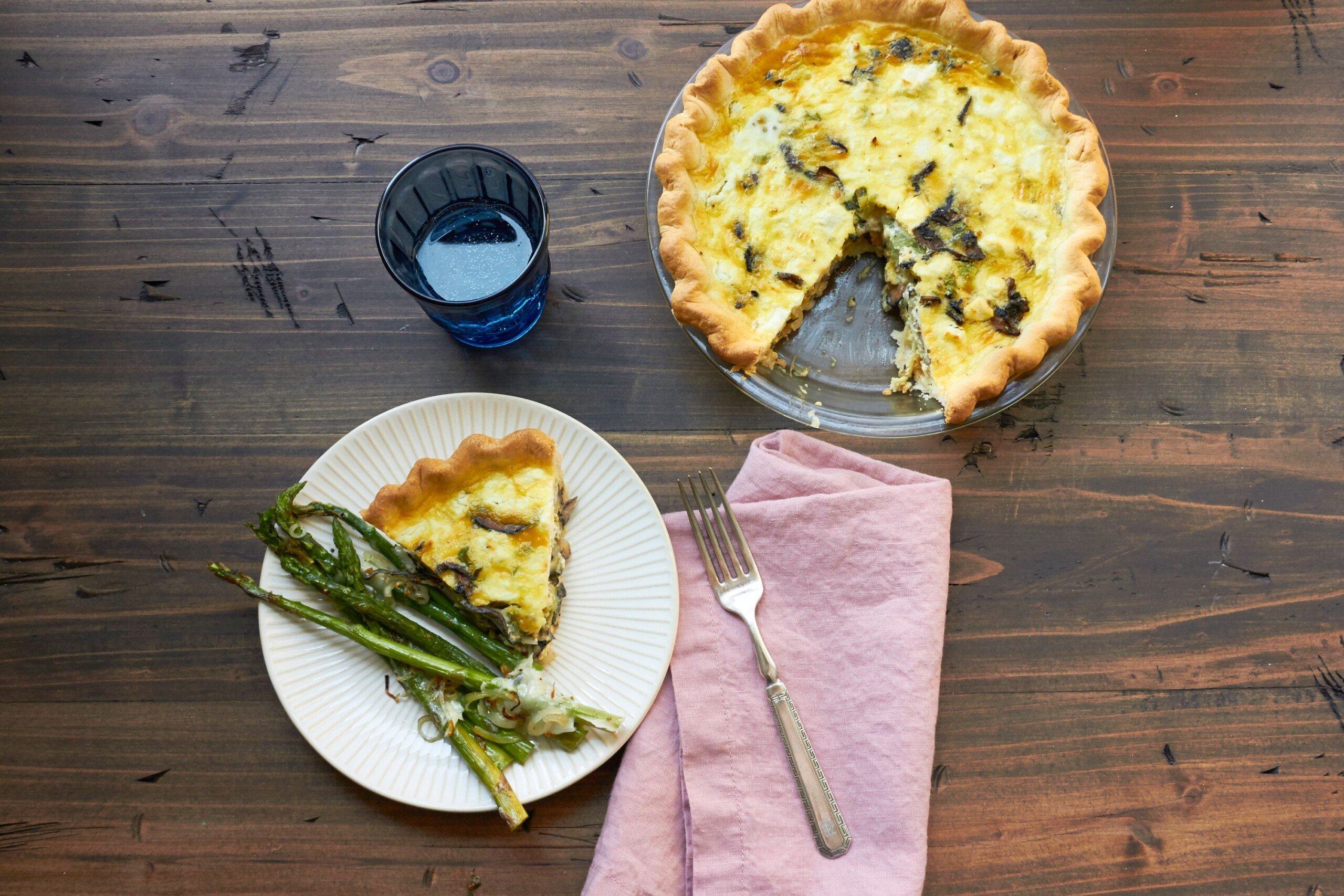 Leek, Mushroom and Goat Cheese Quiche in pie plate and served with asparagus.