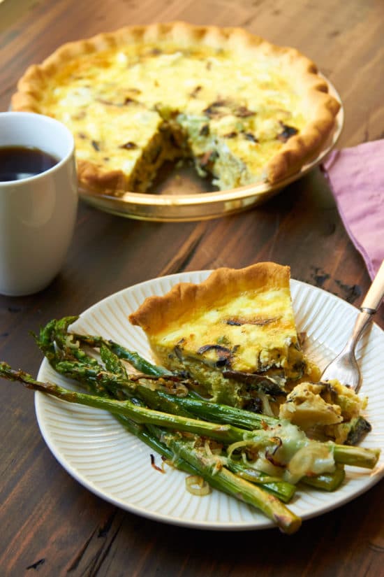 Slice of Leek, Mushroom and Goat Cheese Quiche on a plate with asparagus.