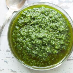 Ramp sauce in bowl next to spoon on white table.