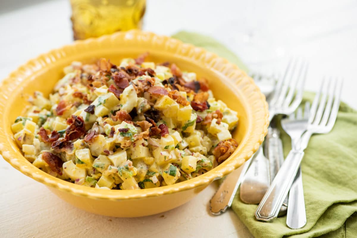 Yellow bowl of Egg and Potato Salad with Bacon.