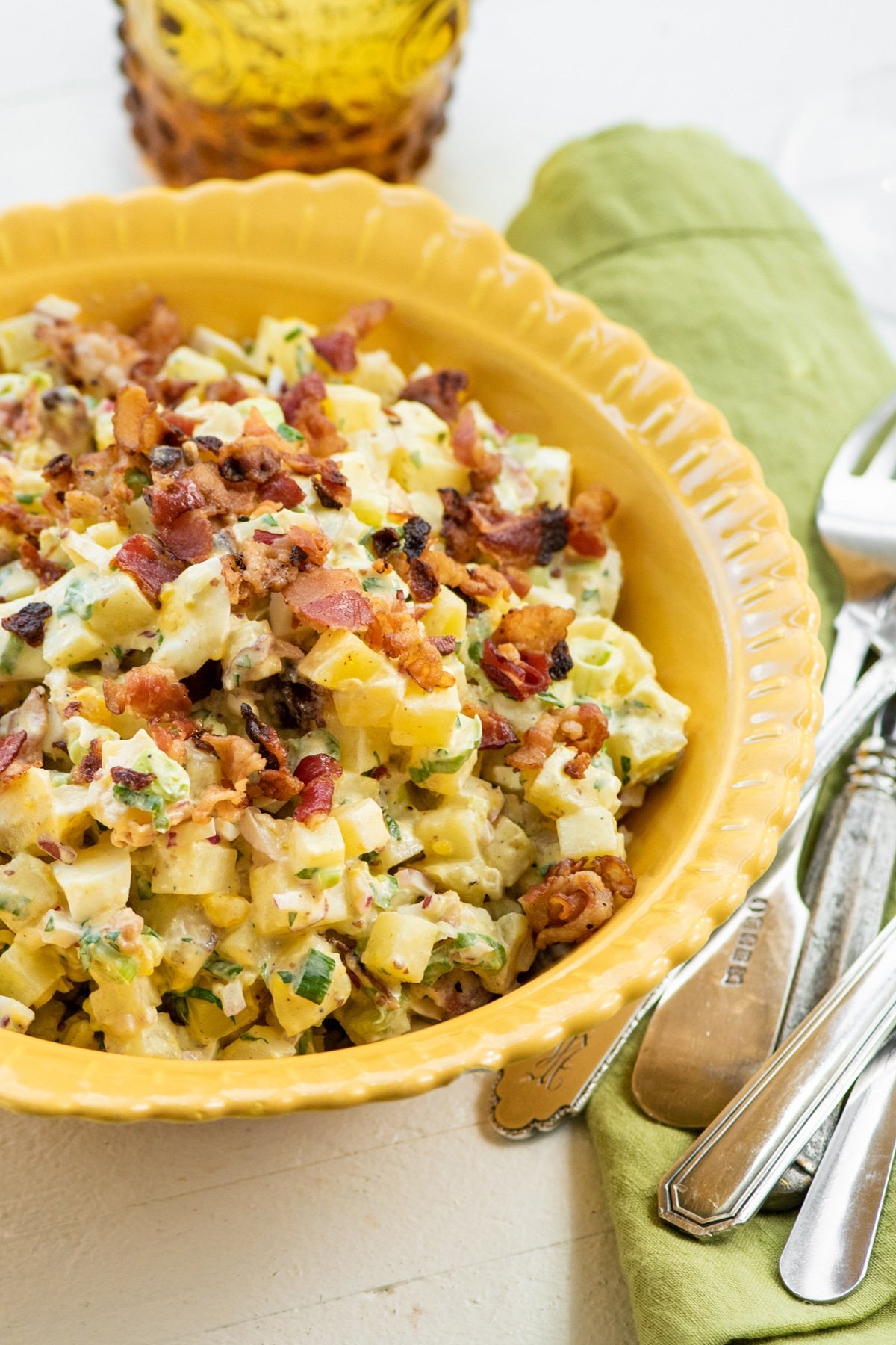 Egg and Potato Salad with Bacon piled high in a yellow bowl.