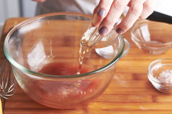 Woman pouring vinegar into a glass bowl.