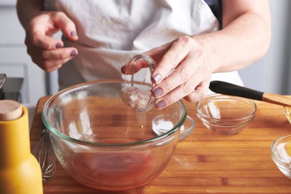 Woman pouring minced shallots into a bowl.