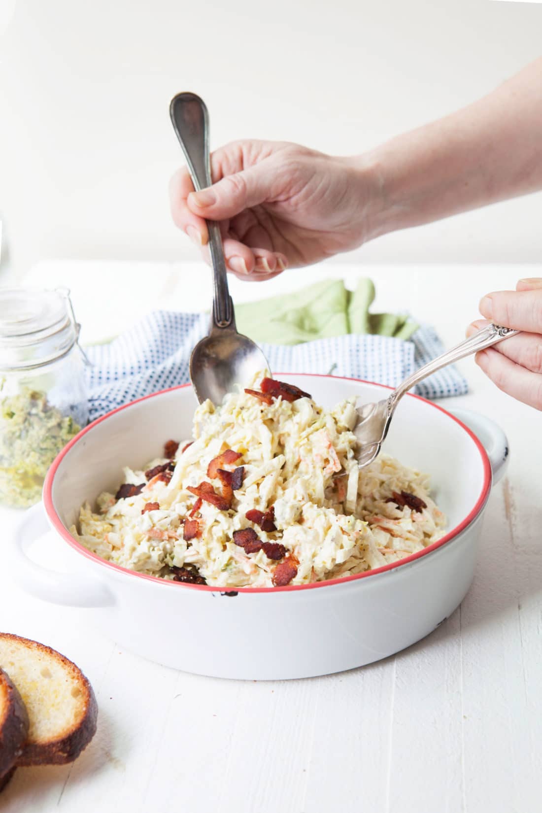 Two spoons scooping Creamy Blue Cheese and Bacon Coleslaw from a bowl.
