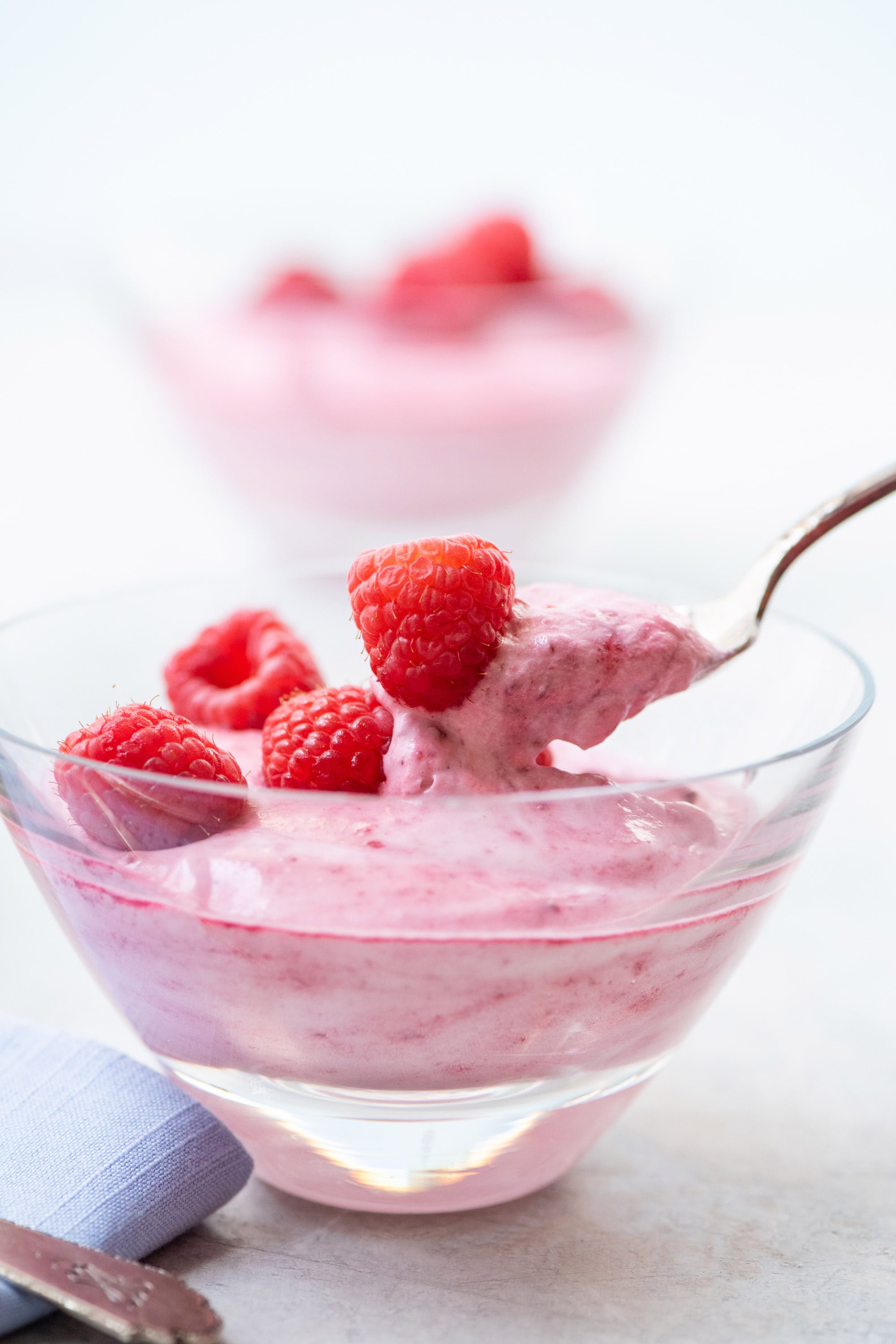 Eating fresh berry-topped raspberry fool with spoon.