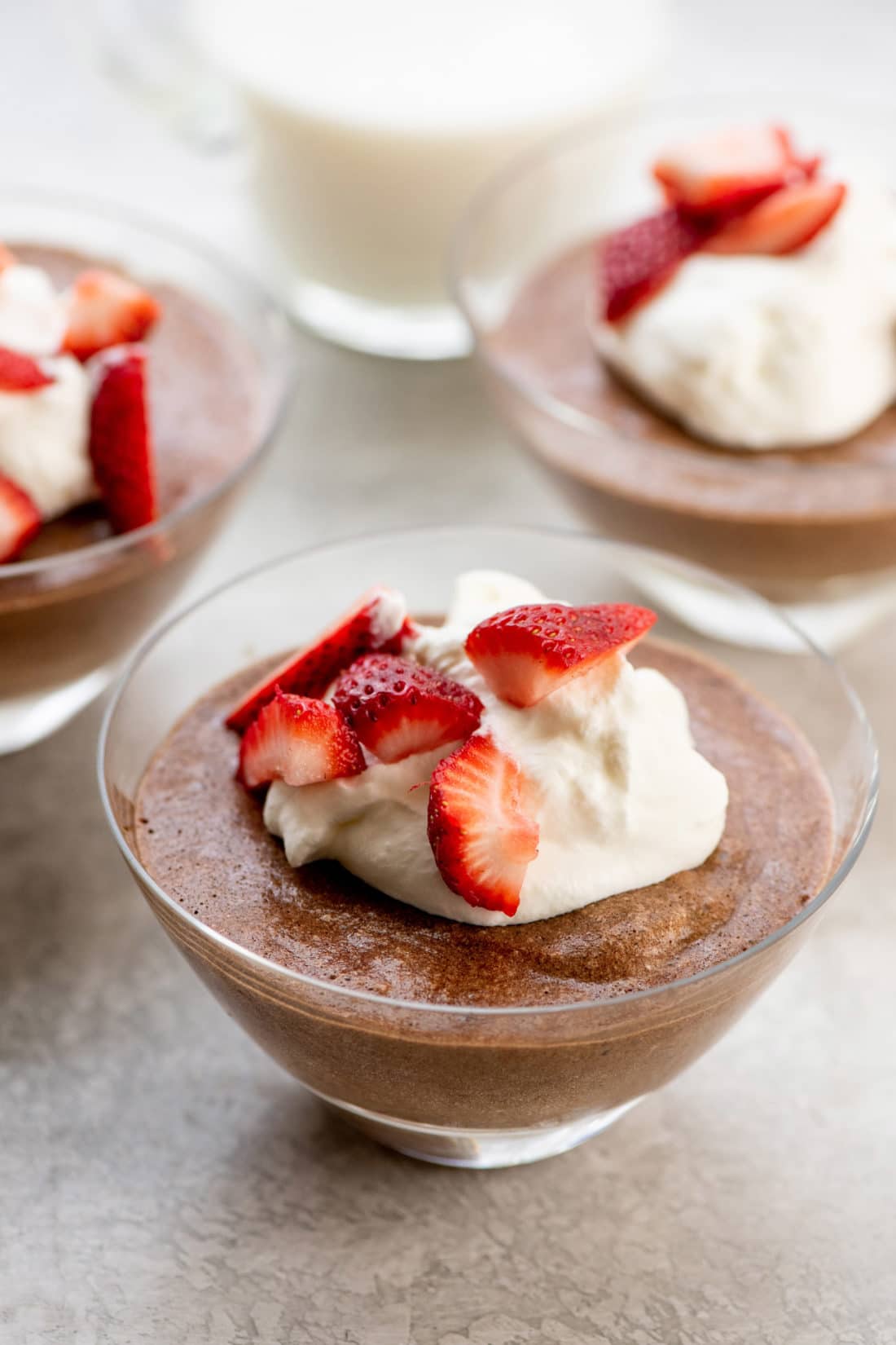 Dishes of Chocolate Mousse topped with whipped cream and strawberries.