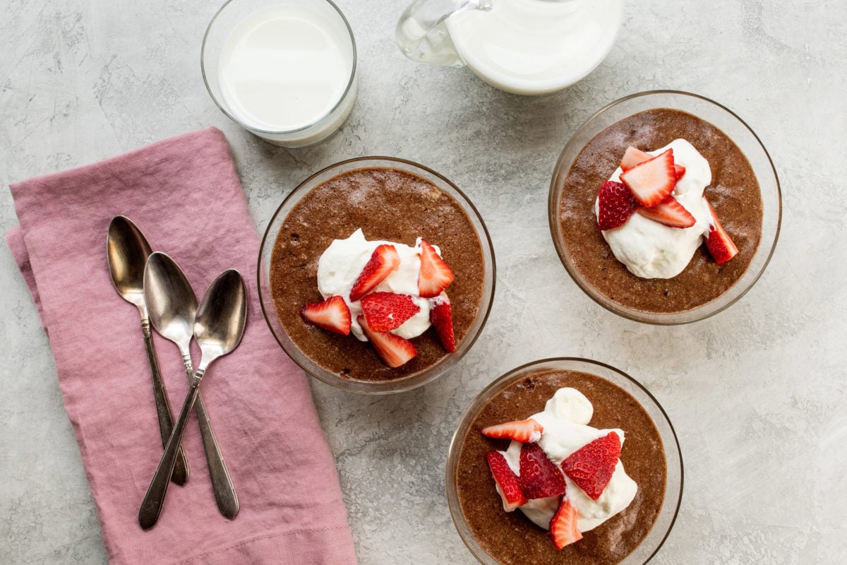 Three dishes of Chocolate Mousse topped with whipped cream and strawberries.