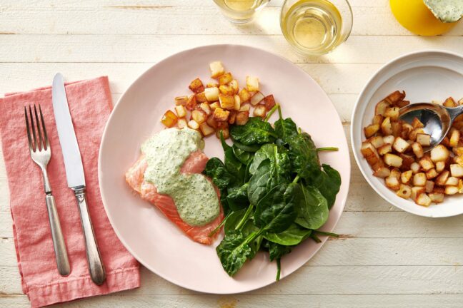 Potatoes, spinach, and Poached Salmon with Cilantro Sauce on a white plate.