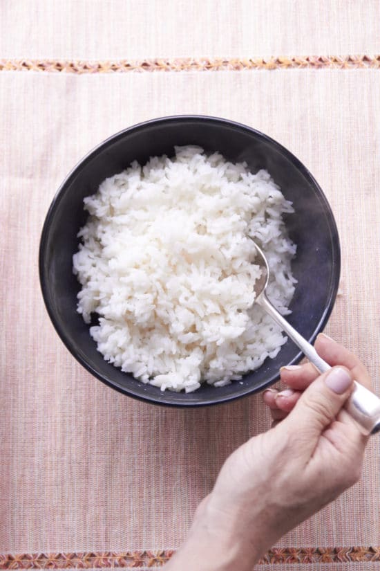 Fluffing rice in a bowl with spoon