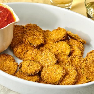 Baked Zucchini Chips and marinara on a white serving dish.