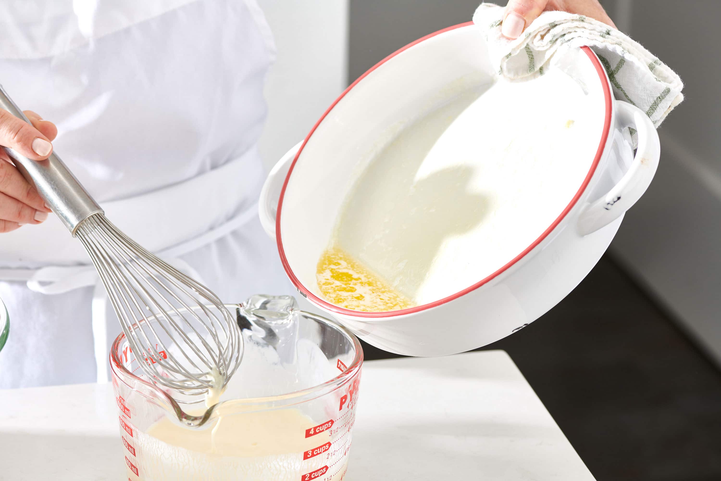 Woman pouring melted butter from a pan into a measuring cup.