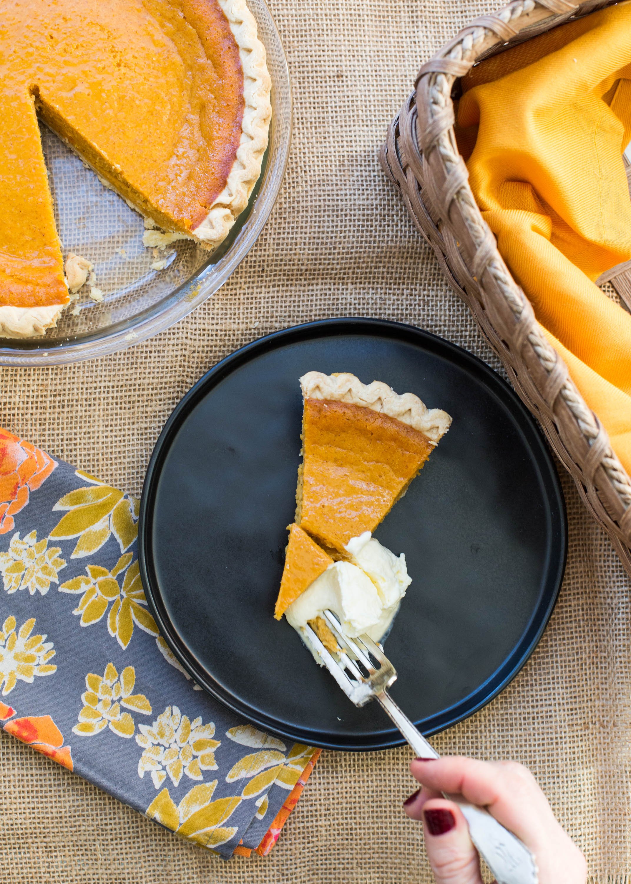 Woman about to scoop up a bite of sweet potato pie with whipped cream.