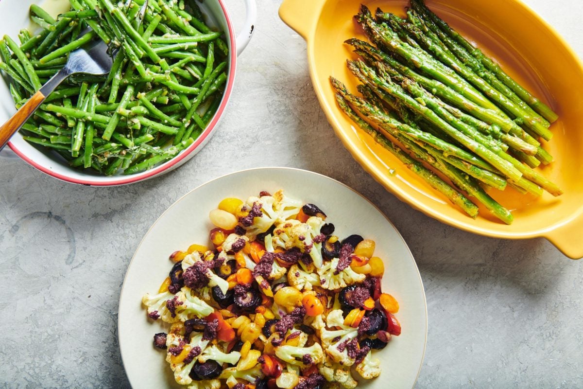 Roasted Cauliflower and Carrots with Olive Drizzle on a counter with other vegetable dishes.