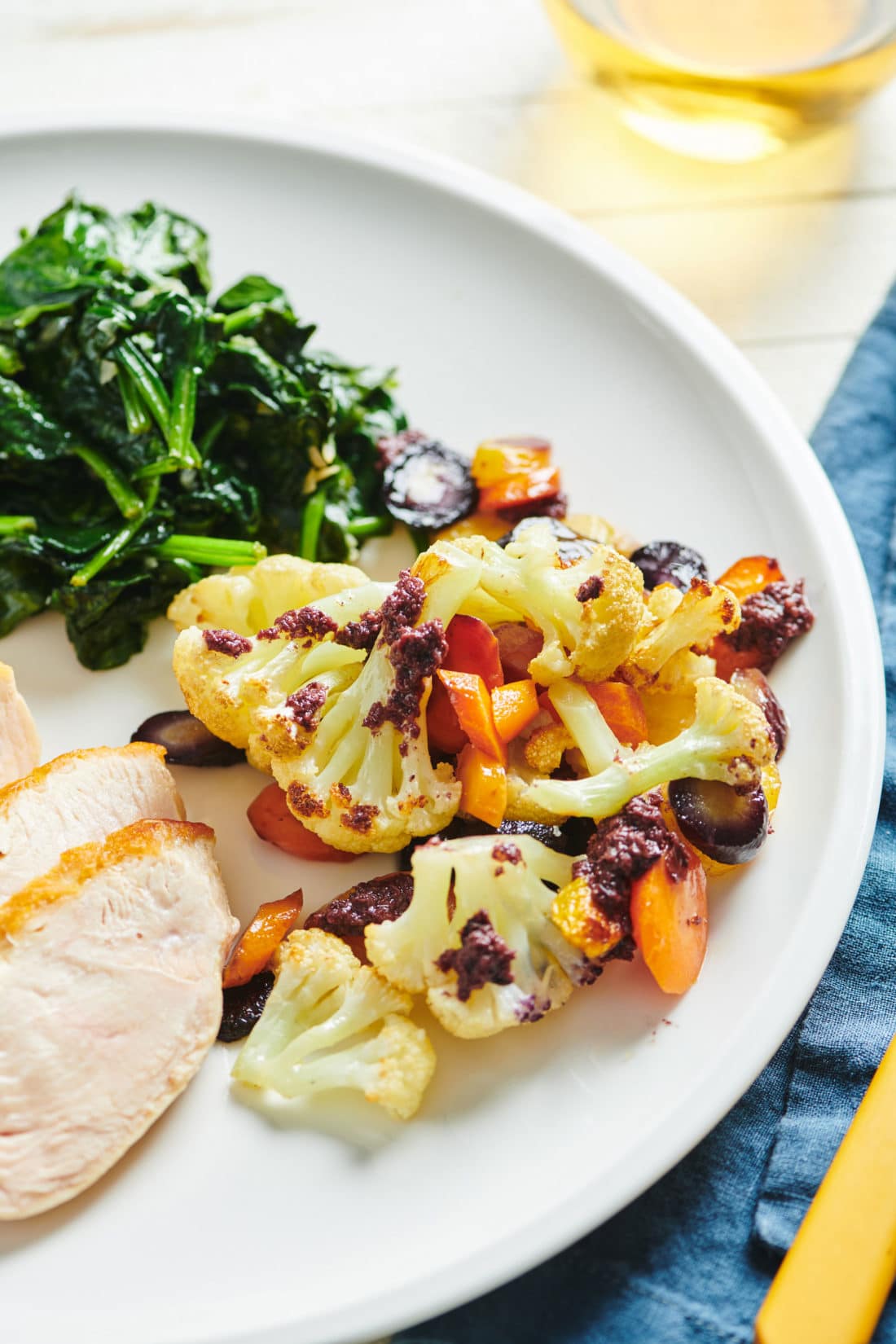 Roasted Cauliflower and Carrots with Olive Drizzle on a plate with greens and meat.