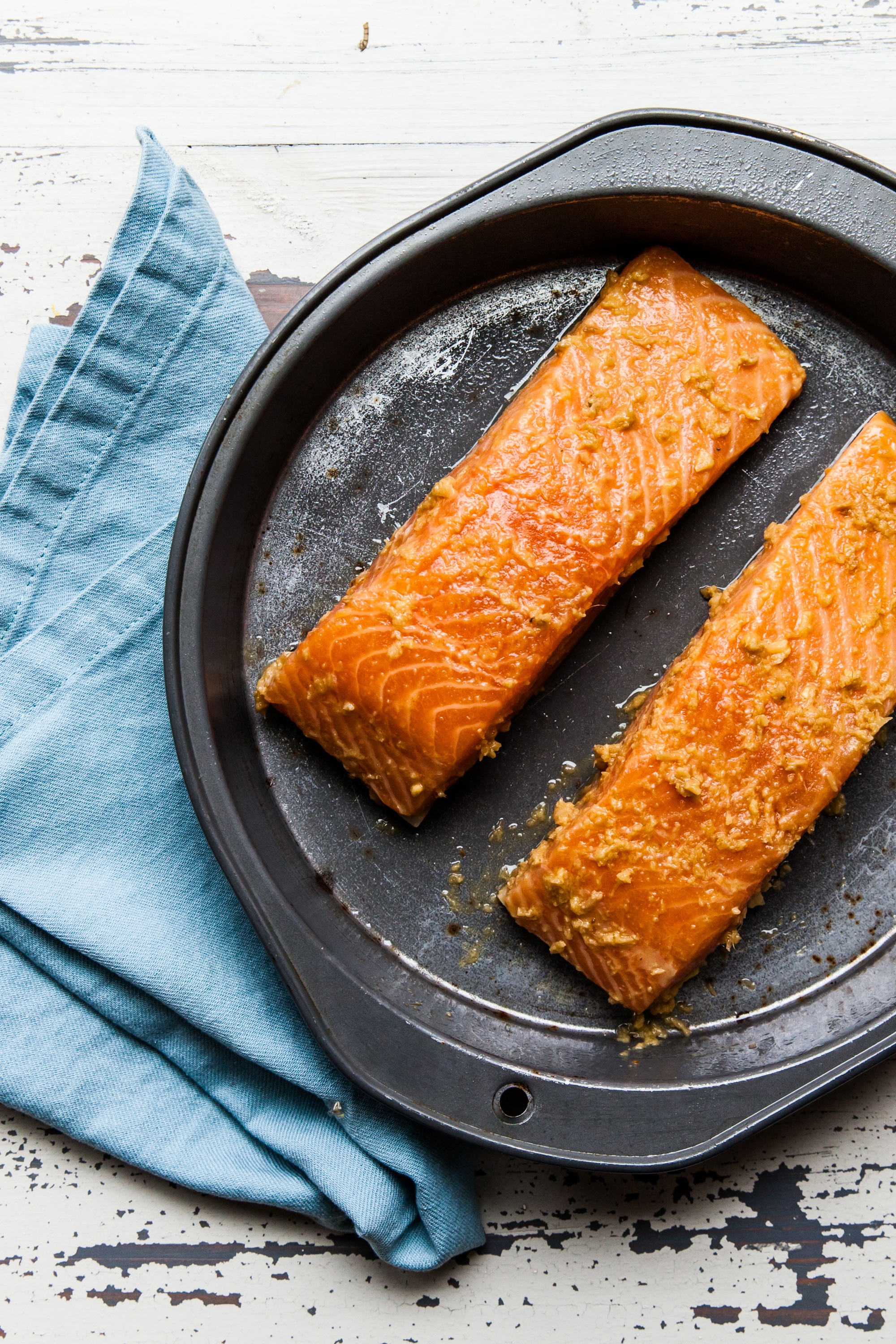 Baked salmon filets with Thai-inspired marinade on baking pan with blue napkin.
