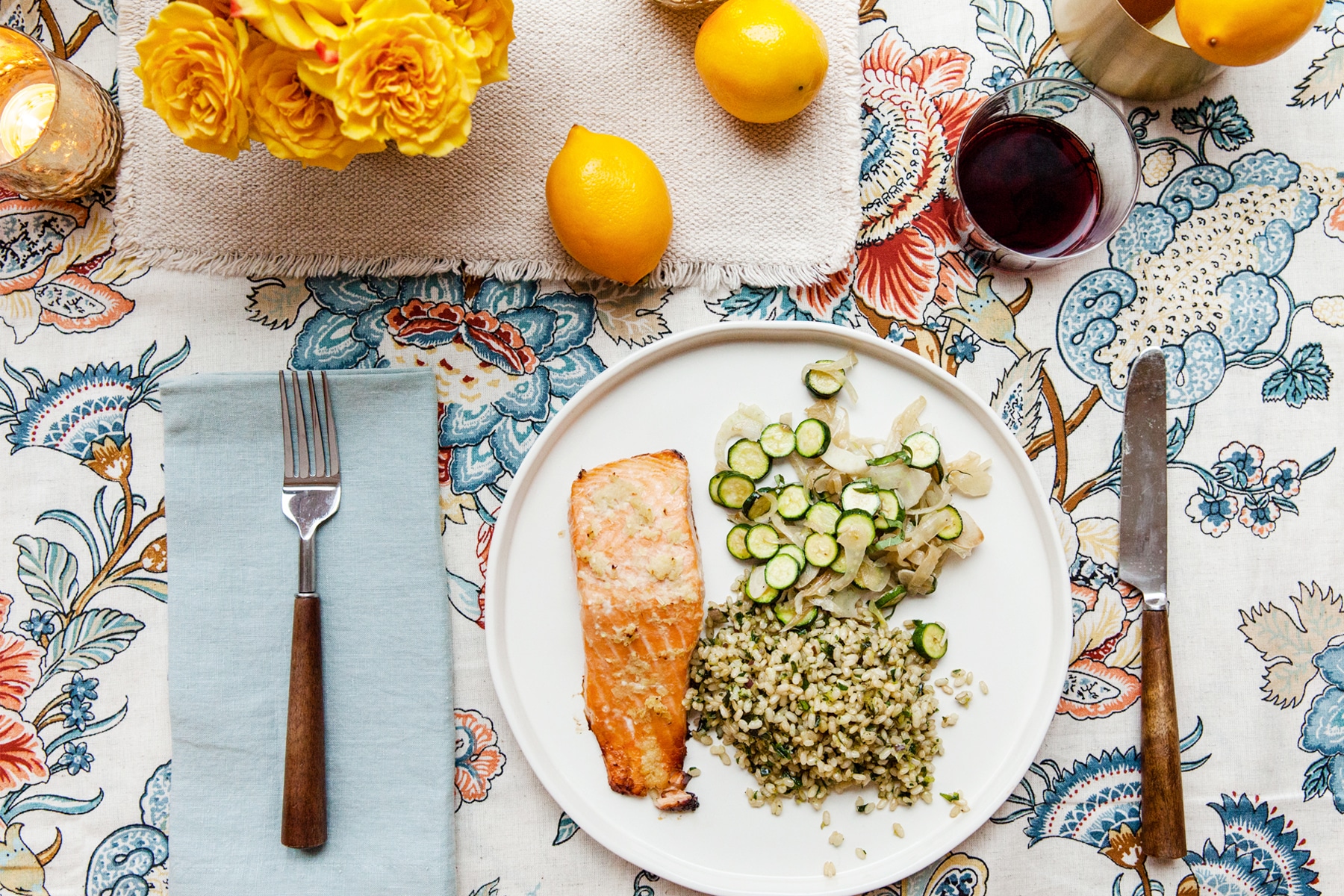 Thai Salmon with Herby Brown Rice and sauteed zucchini on a plate on a flowered tablecloth.
