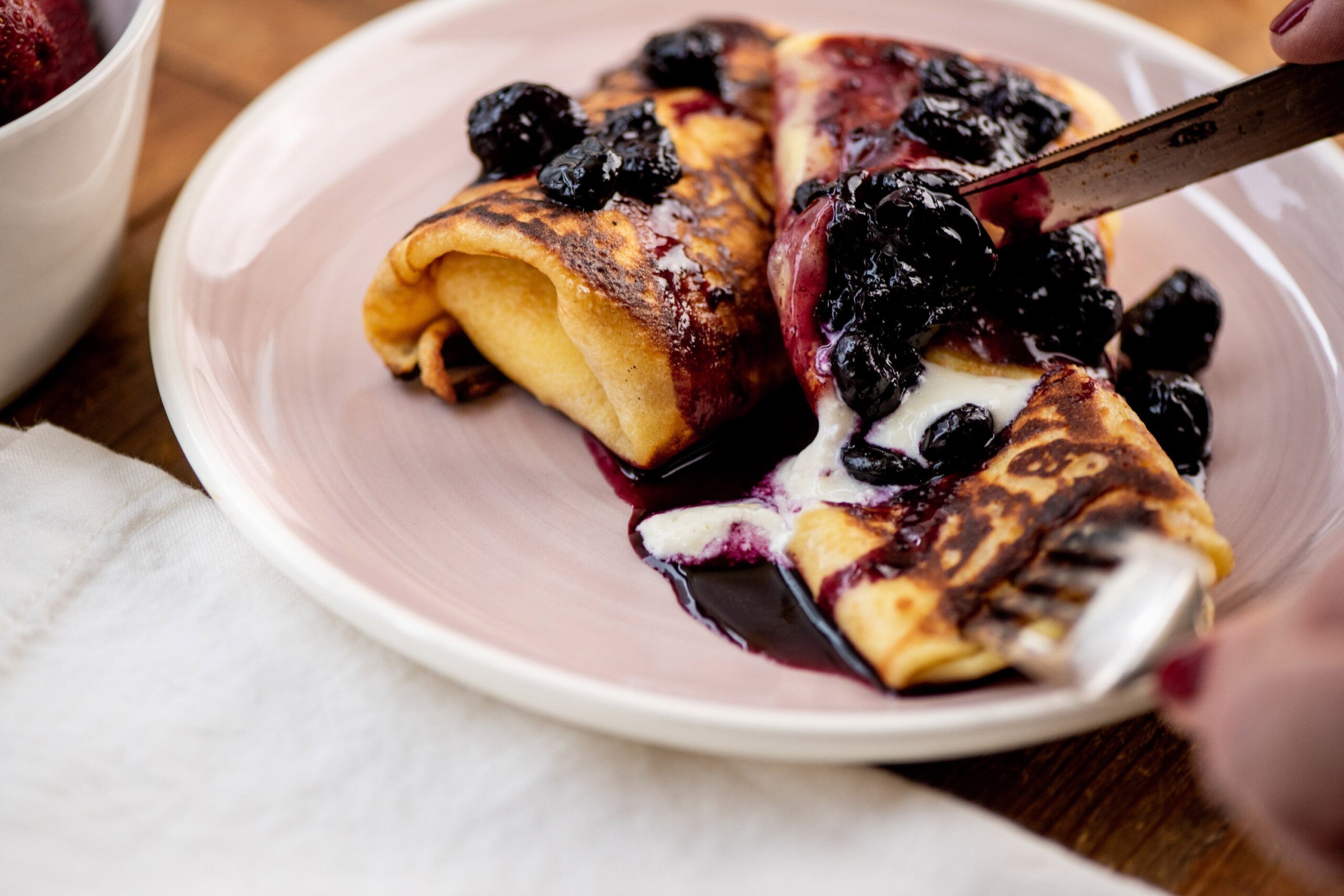 Knife cutting a blintze on a plate.