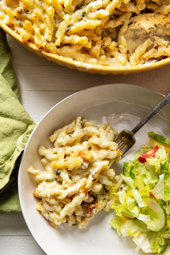 Creamy Four-Cheese Pasta and salad on a plate with a fork.