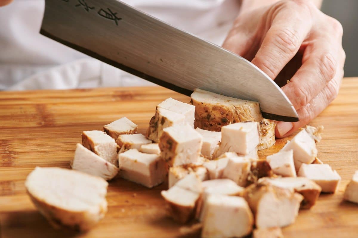 Slicing chicken into cubes.