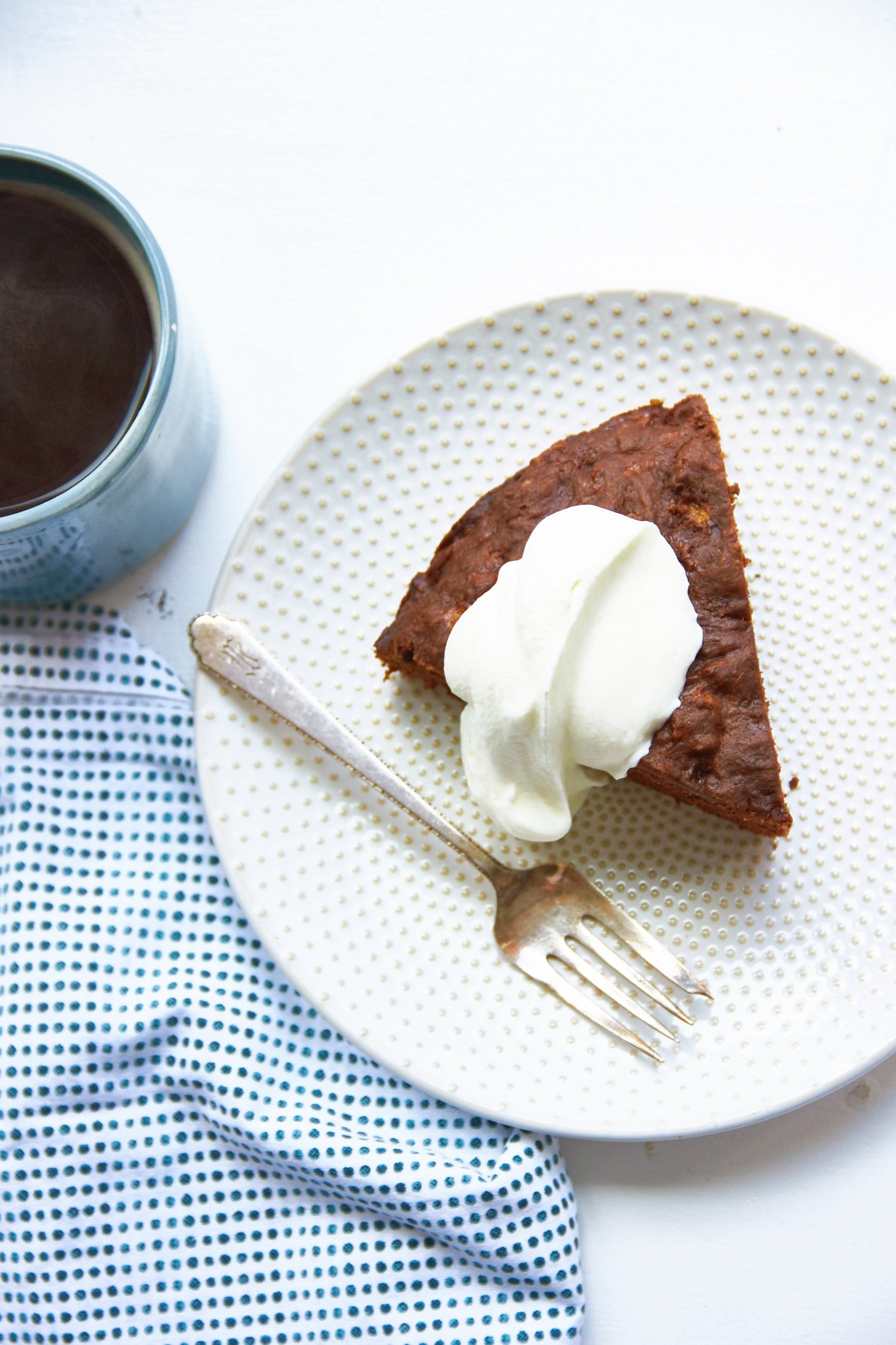 Plate with a fork and a slice of Chocolate Banana Cake topped with whipped cream.