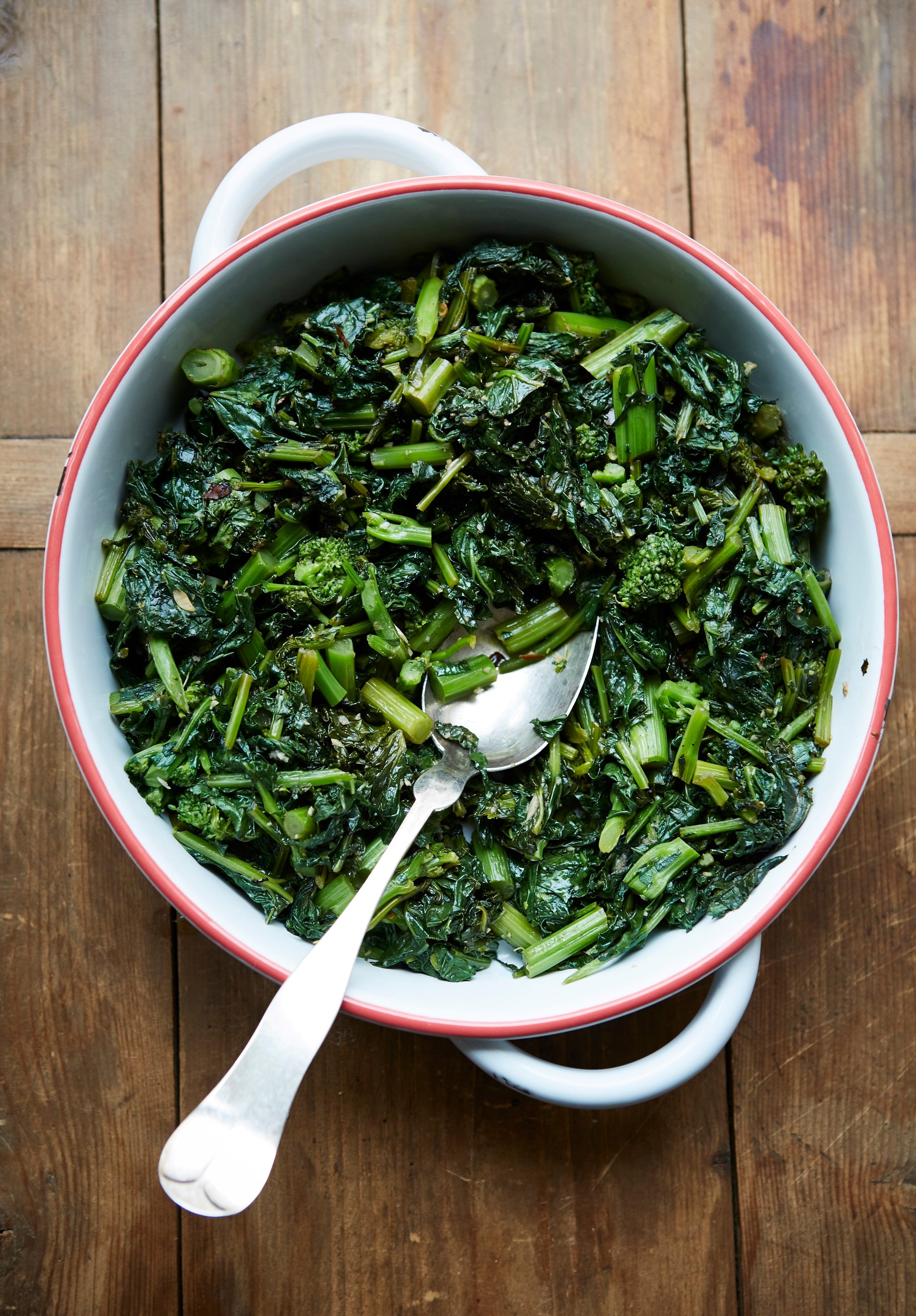 Sautéed Broccoli Rabe in white pan with spoon.