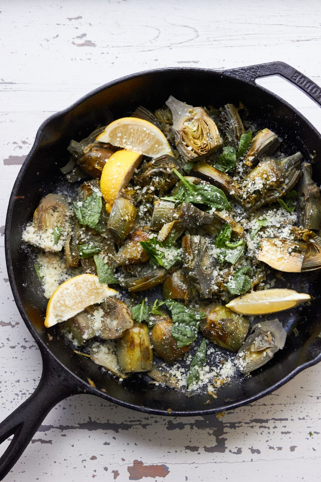 Braised Baby Artichokes with Leeks and Capers in a skillet.