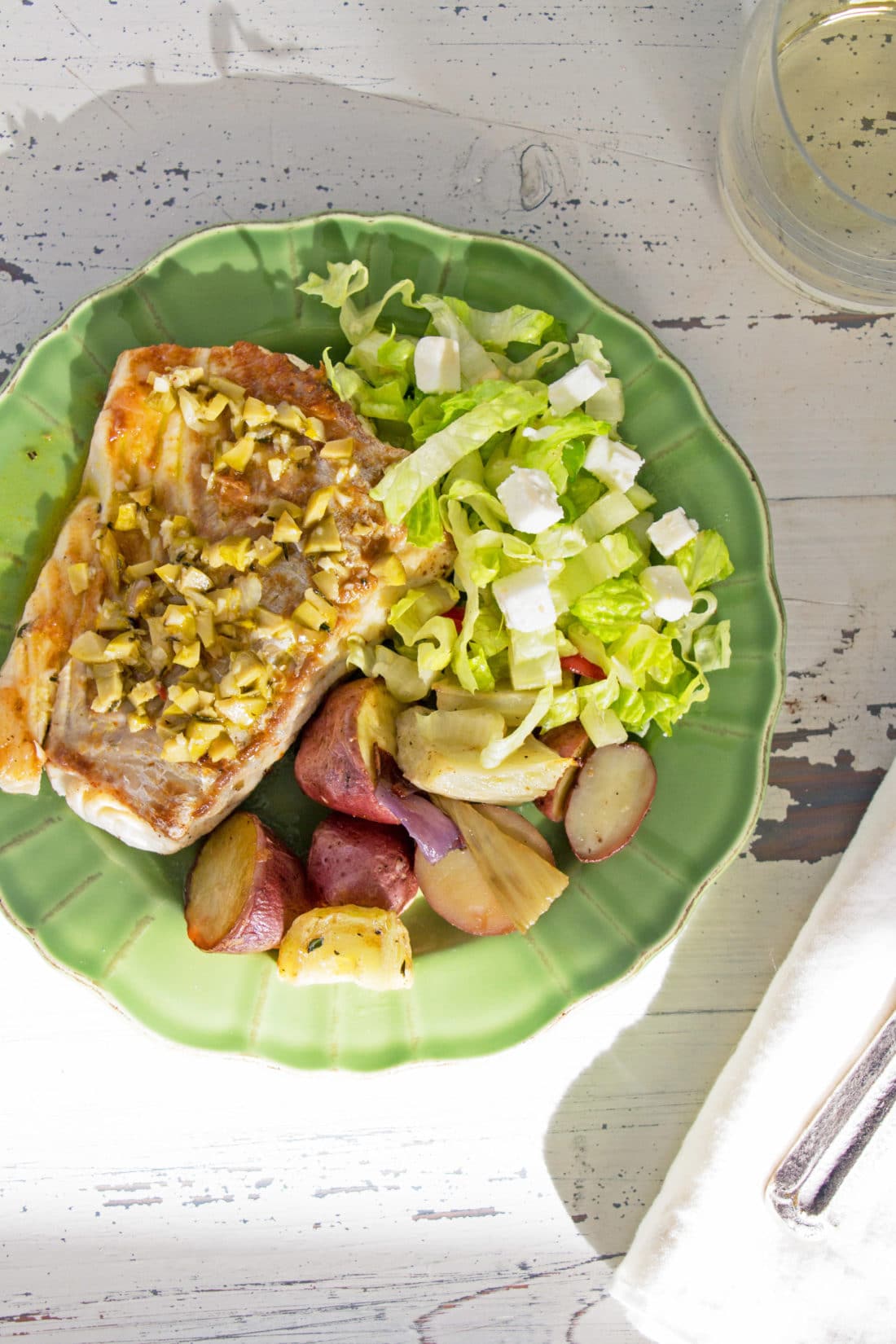 Green plate of Rosemary Orange Cod Fillet, potatoes, and salad.