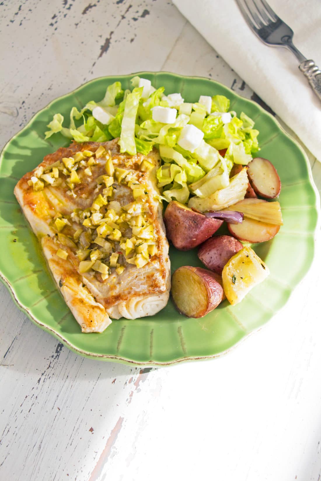 Rosemary Orange Cod Fillet on a plate with salad and potatoes.