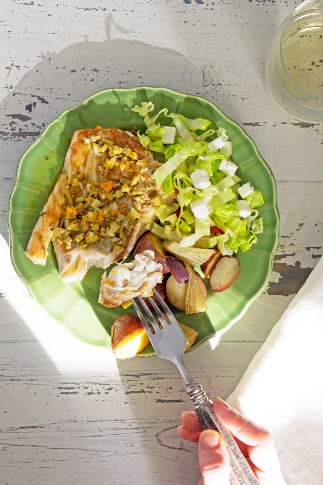 Fork grabbing a piece of Rosemary Orange Cod Fillet from a plate.