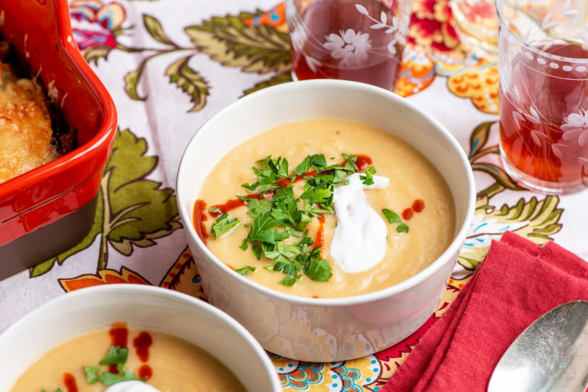 Bowl of Creamy Rutabaga, Parsnip and Cheddar Soup with sour cream, sriracha, and parsley.