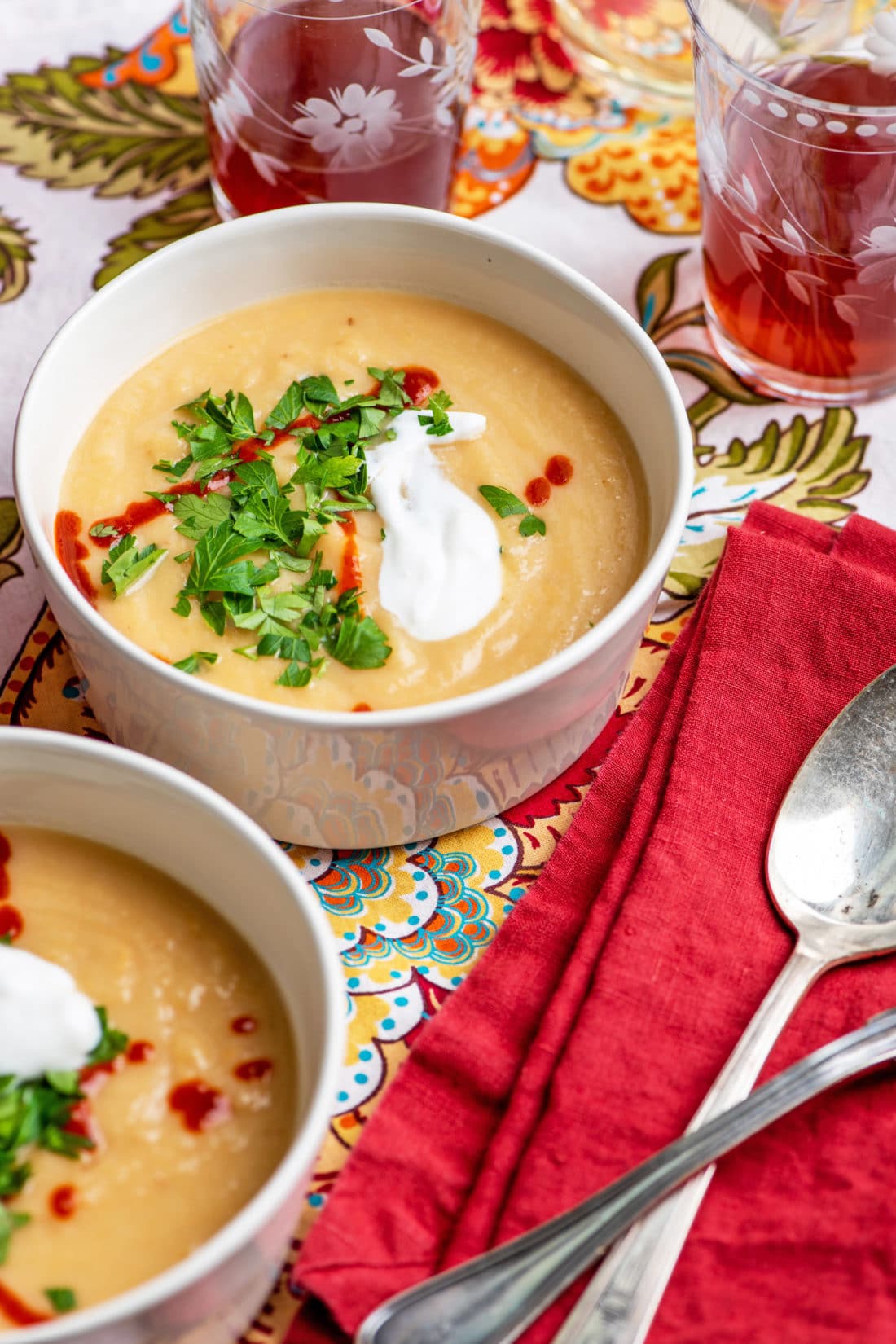 Bowls of Creamy Rutabaga, Parsnip and Cheddar Soup topped with sriracha, sour cream, and parsley.