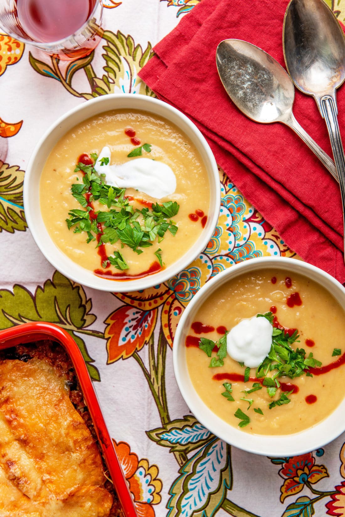 Colorful tablecloth set with two bowls of Creamy Rutabaga, Parsnip and Cheddar Soup.