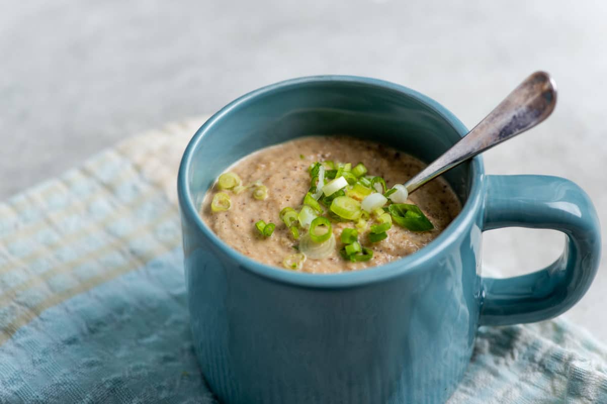 Spoon in a mug of Roasted Cauliflower and Sunchoke Soup.