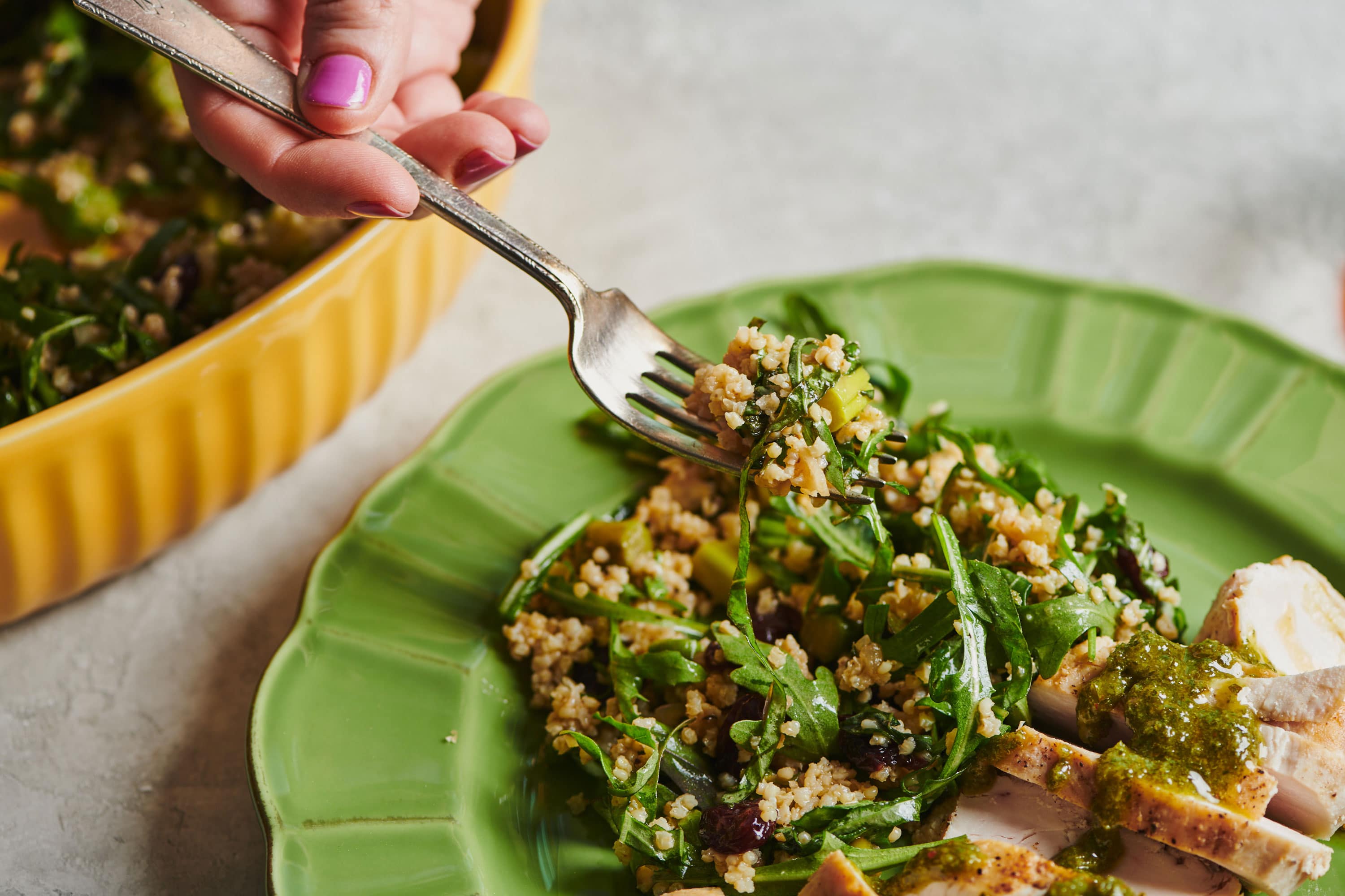Woman scooping Millet and Greens Salad with a fork.