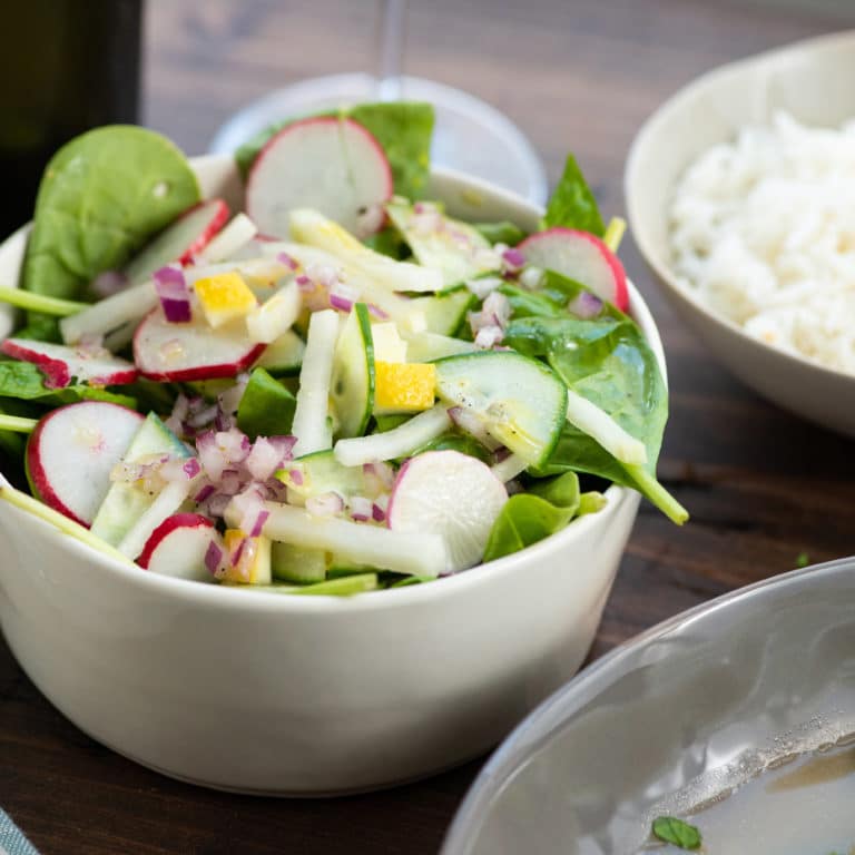Spinach, Radish, and Kohlrabi Salad with Preserved Lemons in white bowl.
