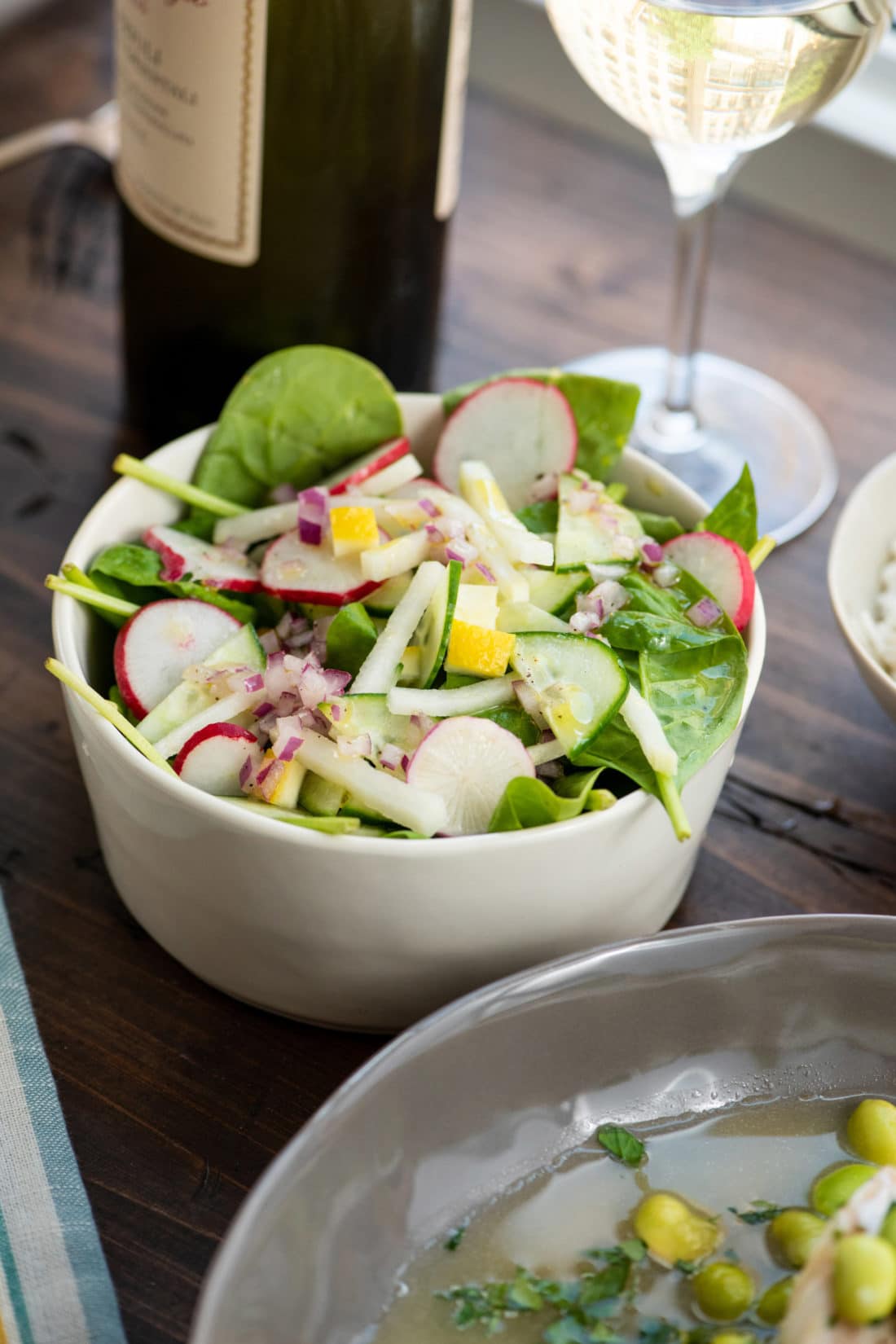 Small white bowl of Spinach, Radish, and Kohlrabi Salad with Preserved Lemons.