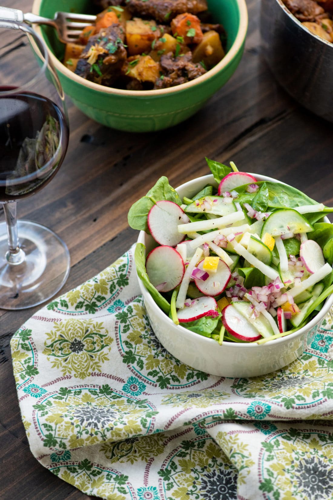 Bowl of Spinach, Radish, and Kohlrabi Salad with Preserved Lemons on a cloth napkin.