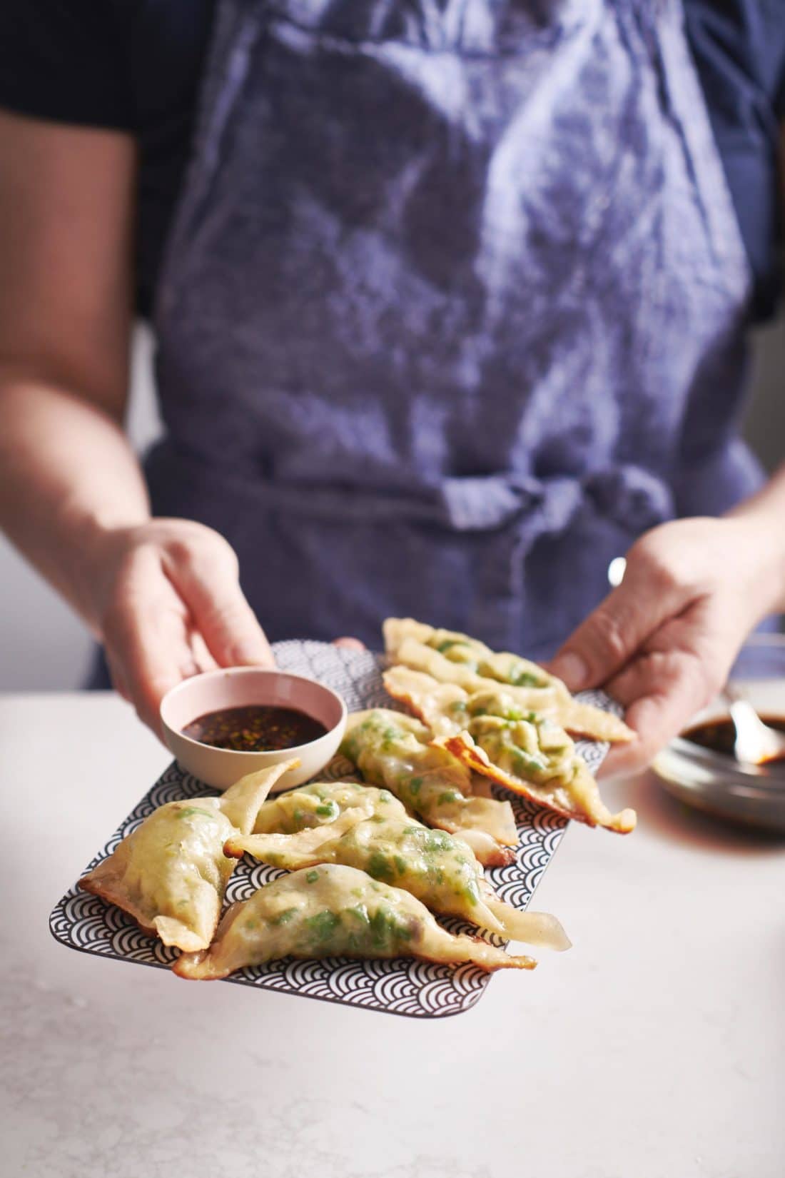 Woman holding a plate of Shiitake Mushroom and Spinach Dumplings.
