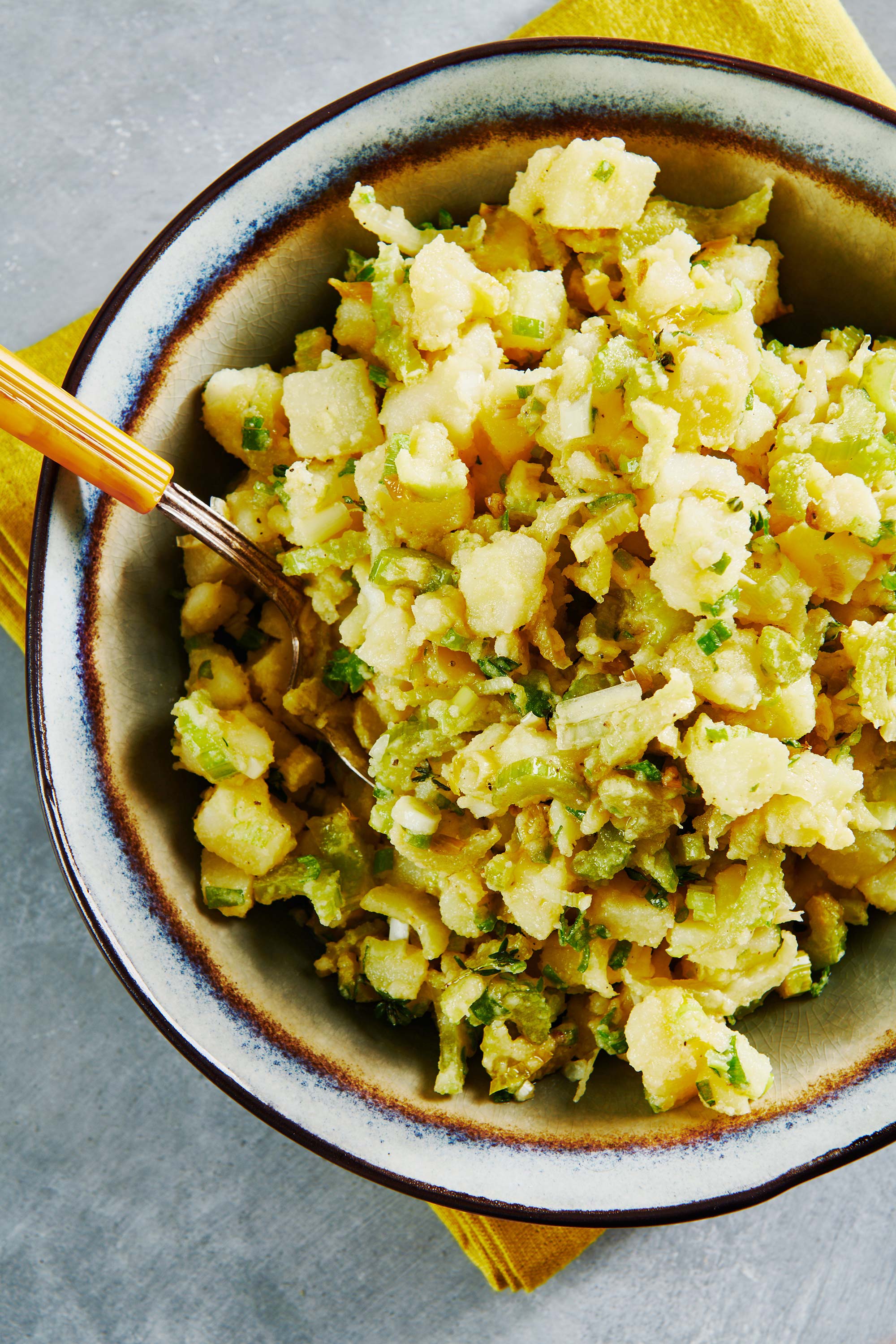 Vegan Potato Salad in a serving bowl with a yellow-handled serving spoon.