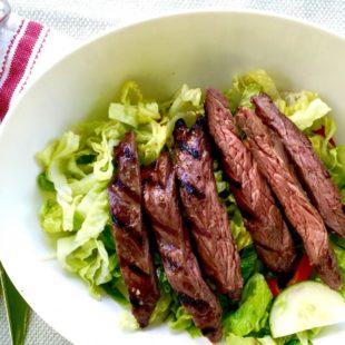 Slices of grilled steak on a salad.