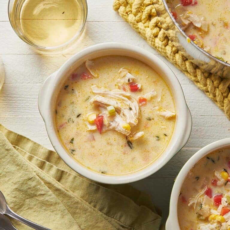 Bowls of Chicken Corn Chowder on a white, wooden surface.