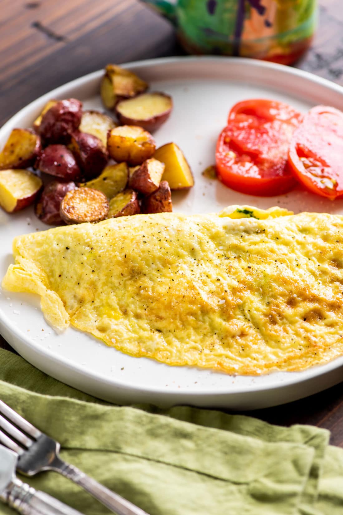 Plate of potatoes, tomatoes, and a Kale Pesto and Goat Cheese Omelet.