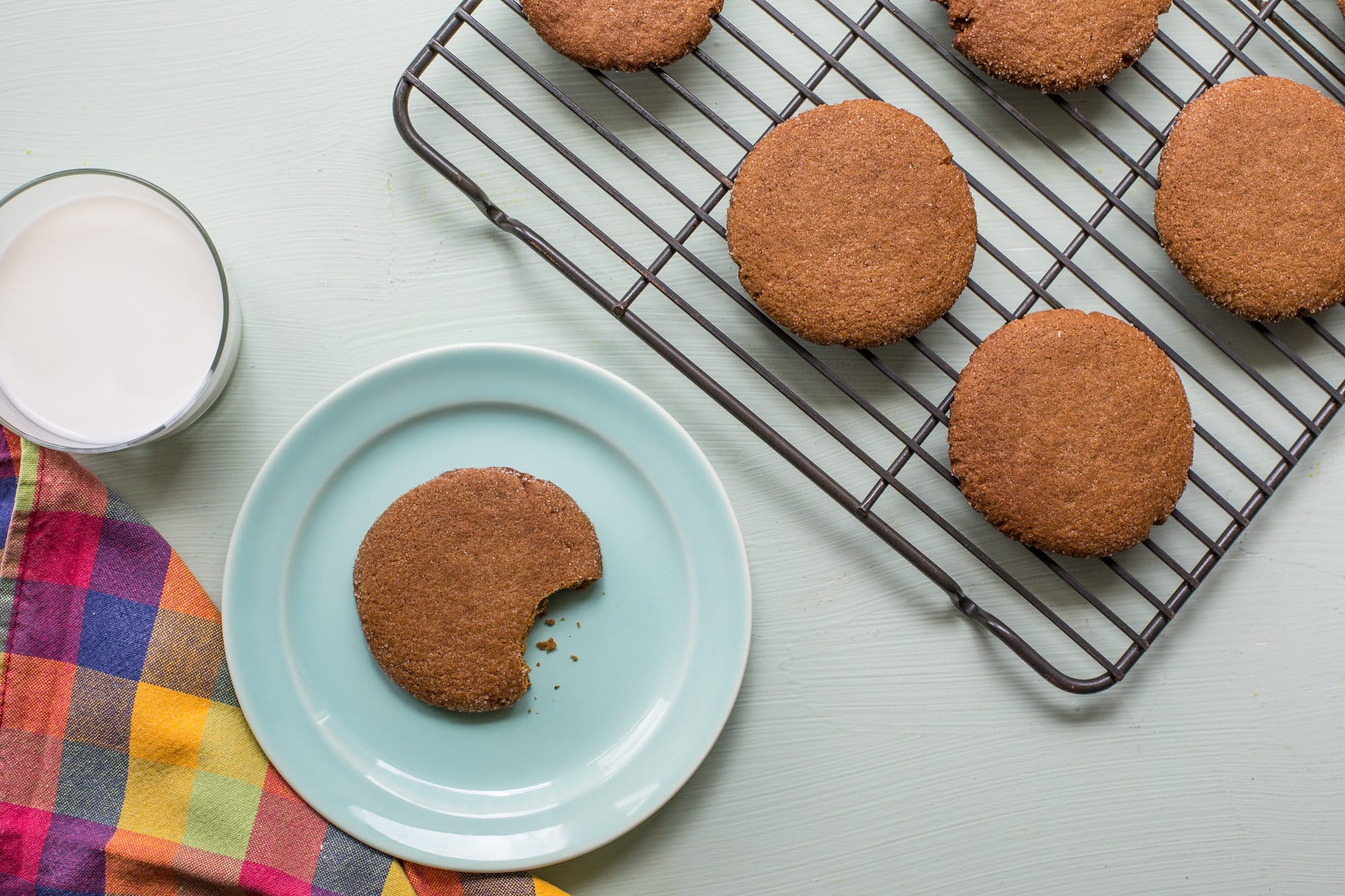 Molasses cookies on wire rack and blue plate with milk.
