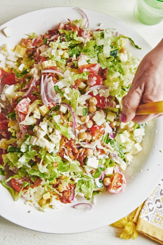 Woman tossing a Late Summer Cobb Salad.