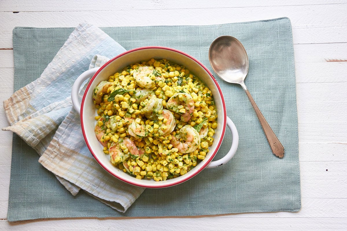 Spoon next to a bowl of Shrimp and Corn Salad with Basil Dressing.