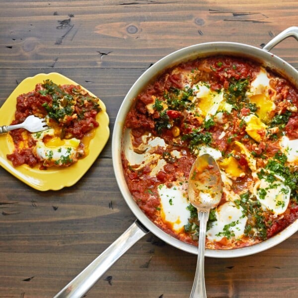Shakshuka with Swiss Chard in frying pan and on yellow plate.